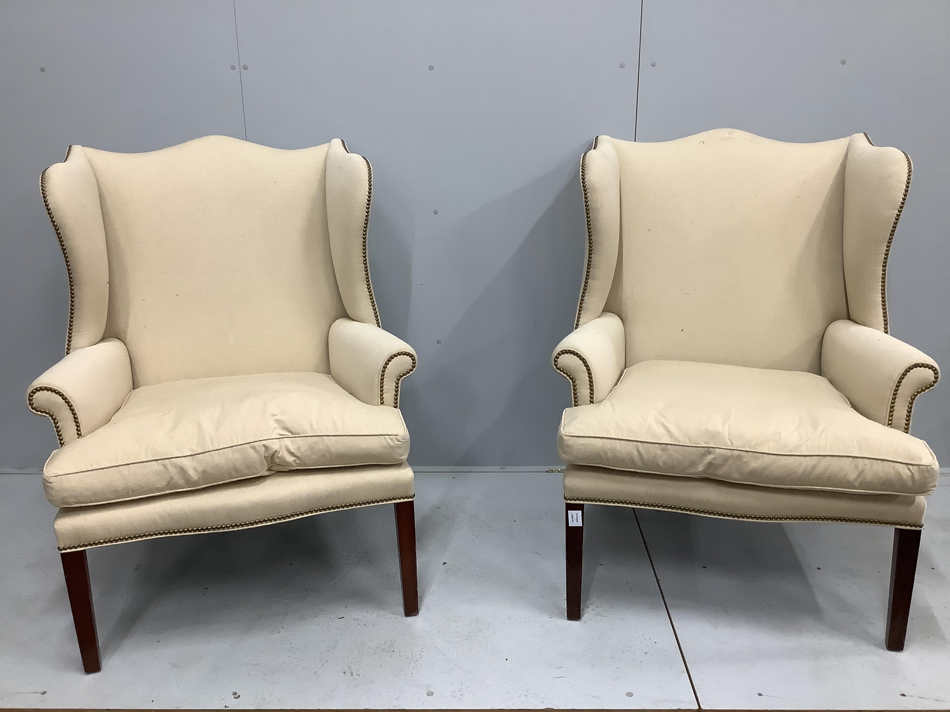 A pair of George III style upholstered wing armchairs, width 90cm, depth 70cm, height 112cm, with footstools